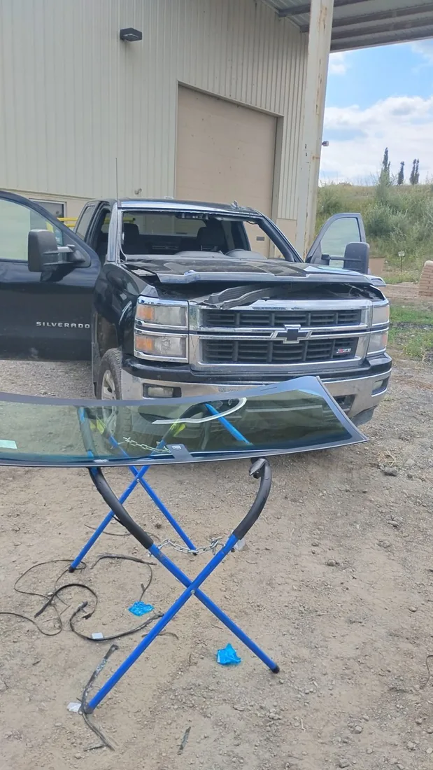 Replacement windshield on a glass rack beside the vehicle